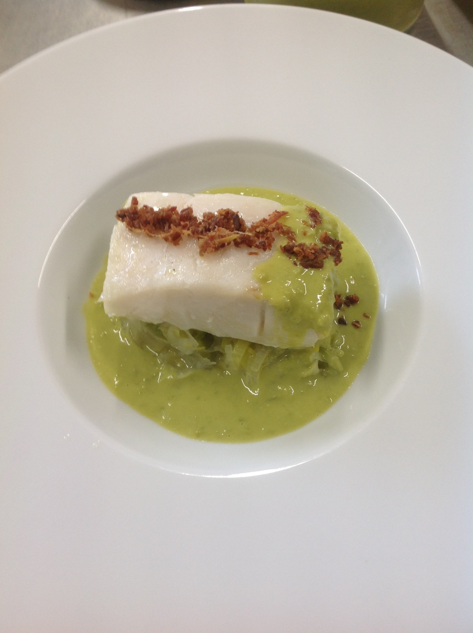 Tronçon de cabillaud, fondue de poireaux, crème de  petits pois, éclats de Serran